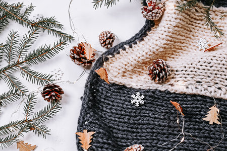 Minimalistic Christmas background. Knitted blanket and spruce branches and snowflakes on a white backgroundの写真素材