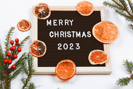 Merry Christmas lettering on letter board. Spruce branches and dried oranges. minimalistic new year...