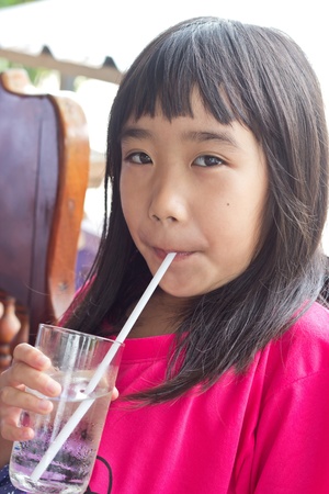 Cute little girl drinking water using drinking strawの写真素材