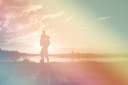 Silhouette Father and daughter playing at lake at the sunset time. Concept of friendly family. Fill color filter.の写真素材