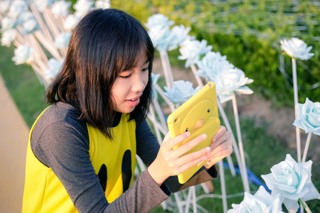 Asian girl using a smartphone photographing flowers in the flower gardenの写真素材