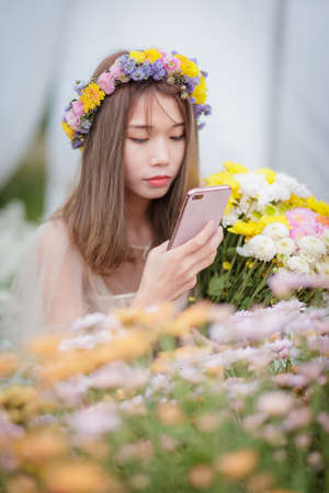 Asian girl using a smartphone photographing flowers in the flower gardenの写真素材