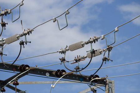 Close up of high voltage power lines on a sunny day with blue sky and white clouds-Stock Photos