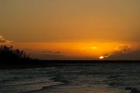 Dramatic sunset with tones of oranges over the ocean in the Caribbeansの写真素材