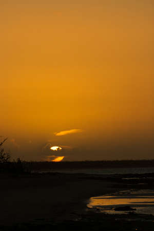 Golden sunset at the beach with a clear sky showing the sun setting behind the seaの写真素材