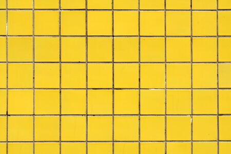 wall cladded with yellow square ceramic tiles for texture