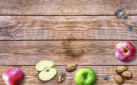 Thanksgiving day with apples, walnuts and berries on an old wooden background. Thanksgiving with seasonal berries and fruits. Extraordinary harvest concept. Autumn background.の写真素材