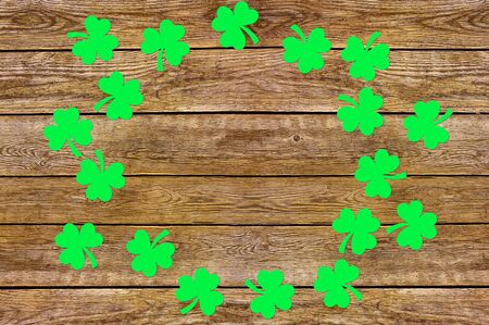 Paper clover leaves on the old wooden background. Lucky shamrock, St.Patrick's day holiday symbol. Space for text, top view.の写真素材