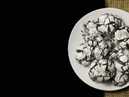 Homemade chocolate cookies. Chocolate brownie cookies in powdered sugar in black background. Selective focusの写真素材