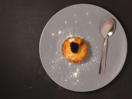 Blackberry muffins with powdered sugar and fresh berry.