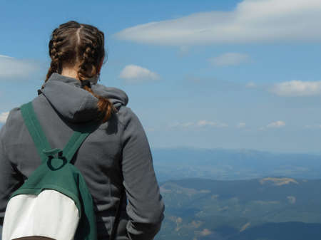 Young girl with backpack enjoying a beautiful nature in mountainsの写真素材