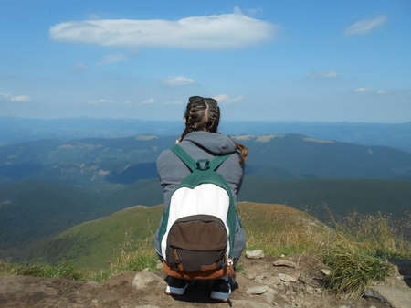 Young girl with backpack enjoying a beautiful nature in mountainsの写真素材