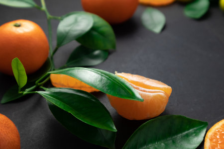 Tangerines or clementines with leaves on a black background. Top view with copy space.