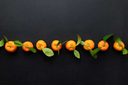 Clementines with leaves on a black background. Top view with copy space.の写真素材