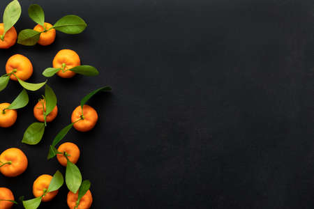 Clementines with leaves on a black background. Top view with copy space.の写真素材
