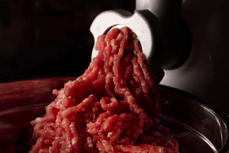 Process of preparing forcemeat by means of a meat grinder. Fresh red mincing close-up on black...