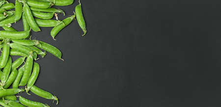 Fresh green peas with pod in bowl on black background