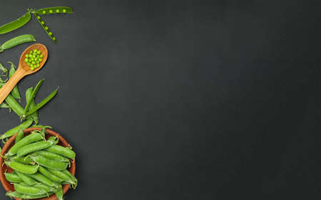 Fresh green peas with pod in bowl and spoon on black backgroundの写真素材
