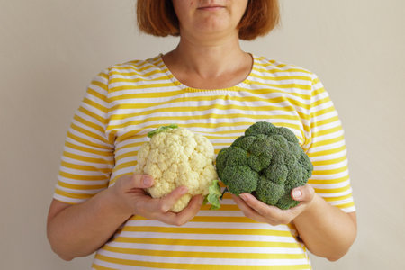 Woman holding broccoli and cauliflower in front of her breasts. Healthcare, medicine and breast cancer concept.の写真素材
