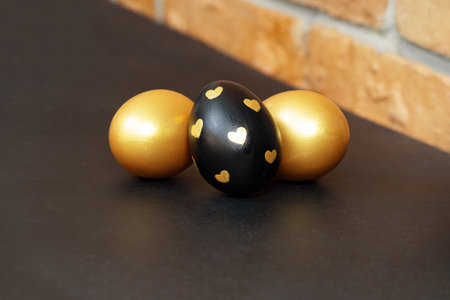 Gold, black and white Easter eggs on a dark gray background.の写真素材