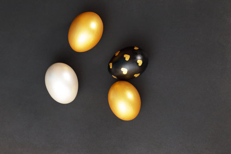 Gold, black and white Easter eggs on a dark gray background.の写真素材