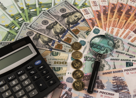 Banknotes spread out on a table with a calculator and a magnifying glass.の写真素材