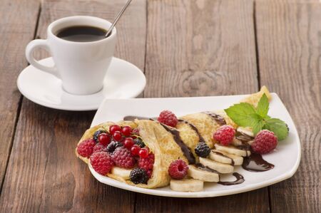 Cup of coffee and pancakes with berries and chocolateの写真素材