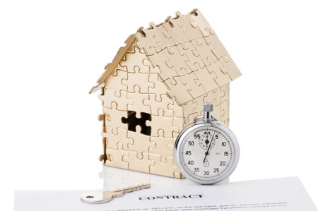 home of gold color puzzles with a stopwatch and a keys isolated on white background. Concept: time to buy a houseの写真素材