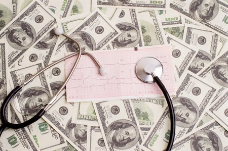 stethoscope over ecg graph on a background of 100 dollar billsの写真素材