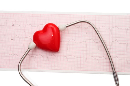 Cardiogram with stethoscope and red heart on table, closeup