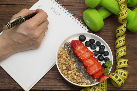 Workout and fitness dieting copy space diary. Dumbbell, vegetable smoothies and measuring tape on rustic wooden tableの写真素材
