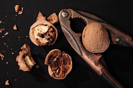 nutcracker, whole and chopped nuts on black backgroundの写真素材