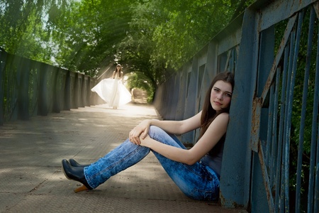 walking girl in flying white dress and sitting near fencing. outdoor shot