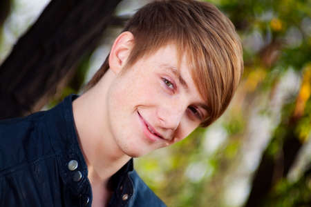 attractive, smiling, red-haired guy on nature. close-up portraitの写真素材