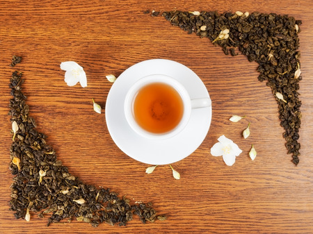 white cup and saucer with jasmine flowers on a wooden table. view from aboveの写真素材