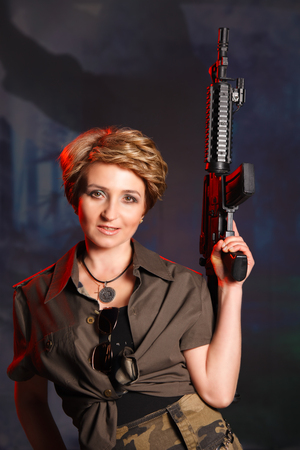 Portrait of attractive woman in military style holding gun in handsの写真素材