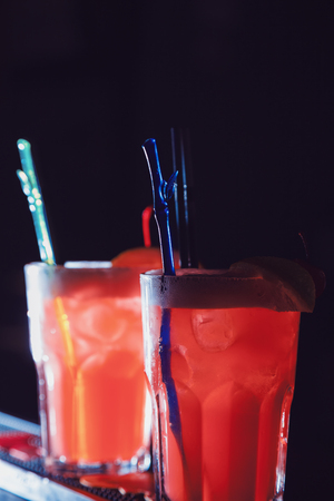 A beautiful red cocktails with slice of orange and cherry in a tall glasses. close-upの写真素材
