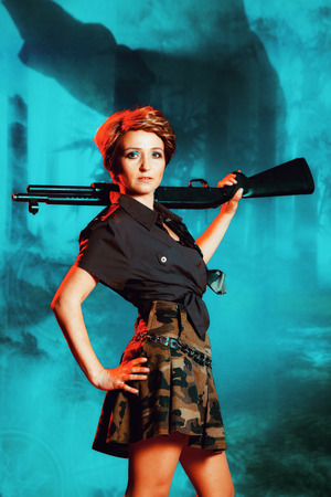 Portrait of attractive woman in military style holding gun in handsの写真素材