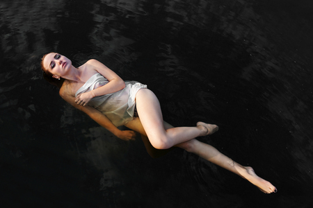 immersion in black waters. Attractive sensual girl in water with reflection of clouds, portrait, fashion, beauty, outdoor, fine artの写真素材