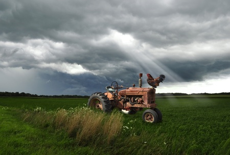 old tractor on a summer field in a  stormy weatherの写真素材