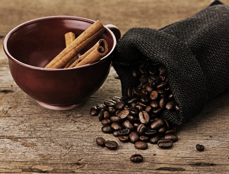 Coffee cup with burlap sack of roasted beans on a rustic table の写真素材