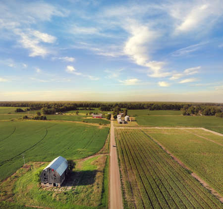 Aerial view of farmlands with an old barn and a dirt road.の写真素材