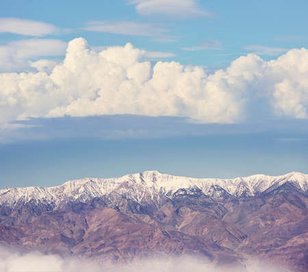 Snowy mountains with clouds on a blue skyの写真素材