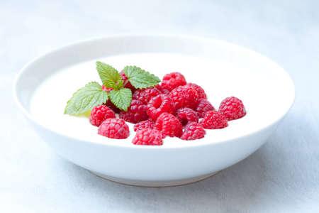 Bowl of yogurt with some fresh raspberries and mint on topの写真素材