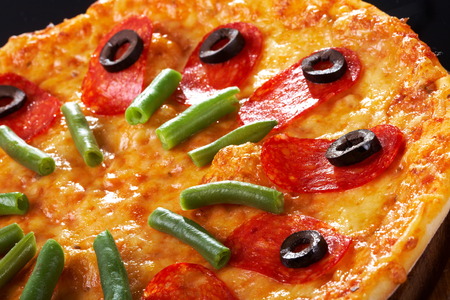 Pizza with salami meat on black backgroundの写真素材