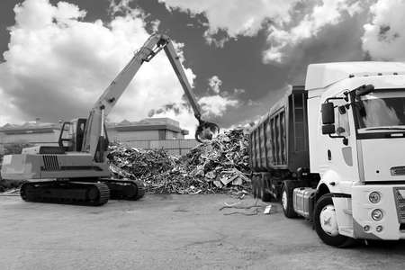 a Black and white photo of a crane loading under the sky with magnificent clouds