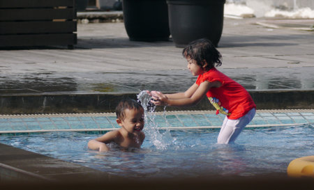 Jakarta, Indonesia-July 15, 2021: Two little boys and girls playing in the water in the swimming poolのeditorial素材