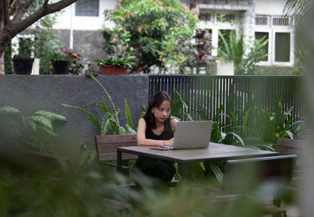 Portrait of a serious businesswoman using laptop in the home garden
