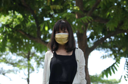 Portrait of an attractive healthy girl, wearing a reusable cotton mask, to avoid contagionの写真素材