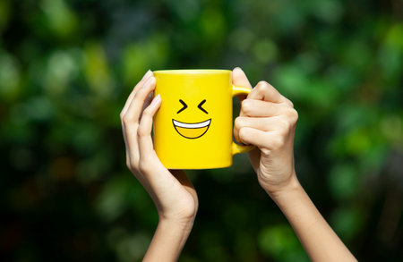Close up of hand holding yellow glass with smiley emoticon, conceptualの写真素材